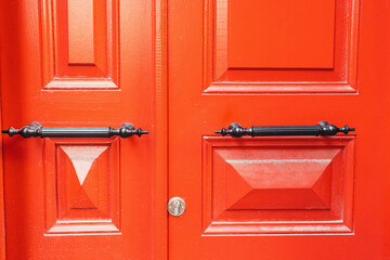 wooden doors, painted in bright red color, with metallic handles