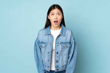 Young asian woman isolated on background looking up and with surprised expression