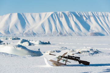 Inuit hunting rifle lying in snow © Mikael