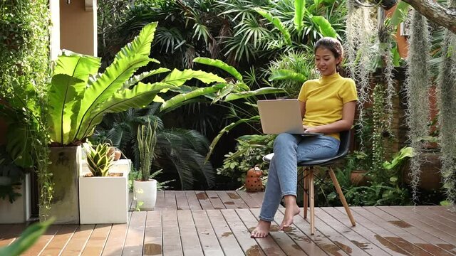 Young people work from home with laptop and drinking coffee in garden nature at home. Asia woman meeting conference connect online with office.  Business and Technology Concept