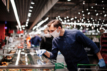 customer in protective gloves looking at the products in the refrigerator