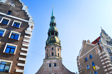 Fototapeta na wymiar Facades of a medieval buildings and St. Peter Church in the foreground in the old town of Riga, Latvia, Baltic States