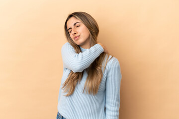 Young caucasian woman isolated on beige background suffering from pain in shoulder for having made an effort