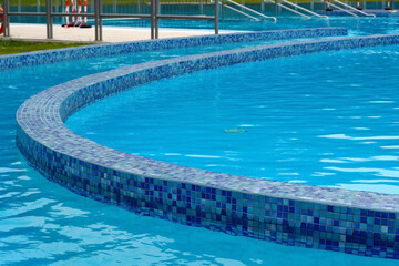 Fototapeta na wymiar blue clear water in an outdoor pool tiled with mosaics side view