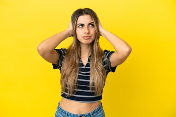 Fototapeta premium Young caucasian woman isolated on yellow background frustrated and covering ears