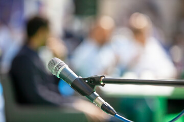 Microphone in focus against blurred people at roundtable event