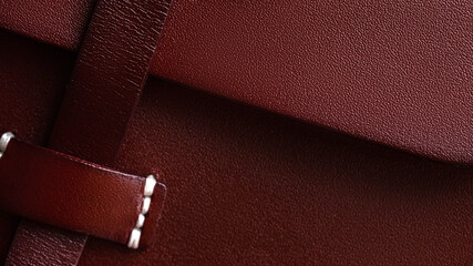 Background part of leather burgundy bag with white thread