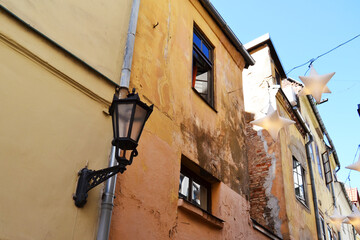 Fototapeta premium Narrow pedestrian street with star shaped lanterns hanging above. Old Town of Riga, Latvia, Baltic States