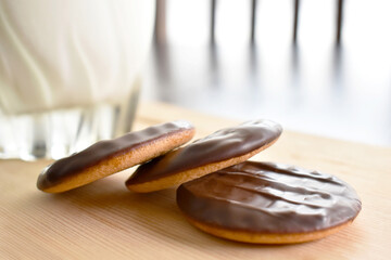 Jaffa cakes with a glass of milk on  a bamboo chopping board. Copy space is on the right side.