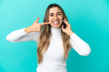 Young caucasian woman using mobile phone isolated on blue background giving a thumbs up gesture