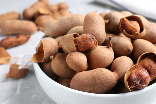 Delicious ripe tamarinds in ceramic bowl on table, closeup