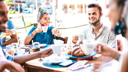 Young people drinking cappuccino at coffee house outdoor - Milenial friends having fun together at restaurant - New normal lifestyle concept with happy guys and girls at cafe bar - Bright vivid filter