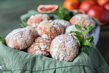 Wooden tray with orange crinkle cookies on green concrete background. Homemade sweet and sour baking.