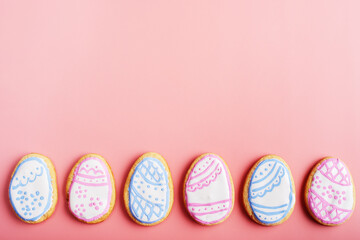 Easter frosted cookies in shape of egg on pink background. Flat lay with copy space.