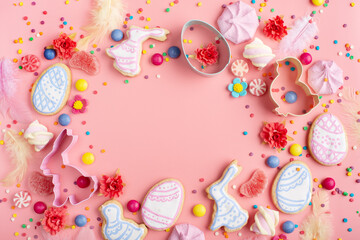 Sugar sprinkles, candies, Cookie cutters, Easter frosted cookies in shape of egg chicken and rabbit on pink background. Flat lay mockup with copy space.