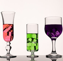 Different types of glasses with colorful drinks backlit scene