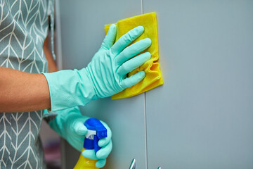 Bearded man cleaning home table surface with towel and gloves, disinfectant spray bottle