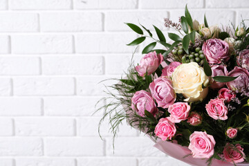 Fototapeta na wymiar Beautiful bouquet with roses near white brick wall. Space for text