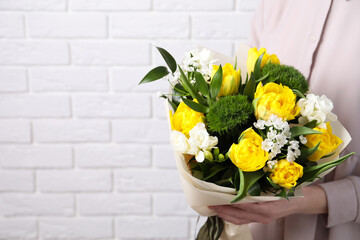 Woman with bouquet of beautiful tulips near white brick wall, closeup. Space for text