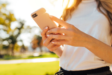Image of woman's hand holding mobile phone outdoors