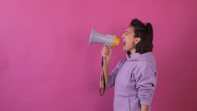Caucasian woman isolated in casual purple shirt on pink background holding megaphone 
