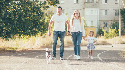 Obraz premium a family with a little daughter and a fox terrier walking in the city on the road