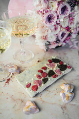 Chocolate bar near to two glasses of champagne and pink flowers