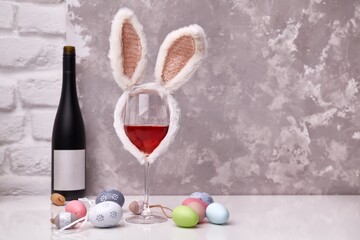 Glass of wine with Easter decorations, colorful eggs on table. Copy space for text.