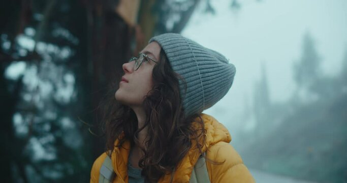 Beautiful young woman stand in middle of forest, look up at sky and tree tops, inhale and breathe in fresh after rain air. Travel adventure Scandinavian tourism concept. Roadtrip wanderlust mood