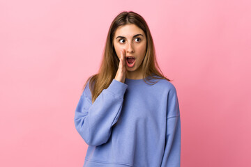 Fototapeta premium Young woman over isolated pink background whispering something with surprise gesture while looking to the side