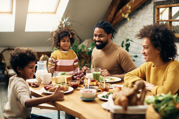 Happy black family enjoying in meal at dining table at home. - Powered by Adobe