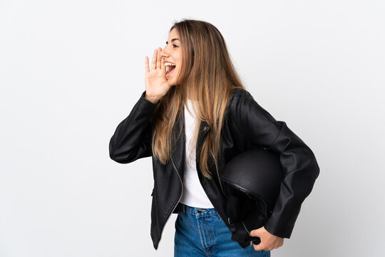 Young Woman holding a motorcycle helmet over isolated white background shouting with mouth wide open