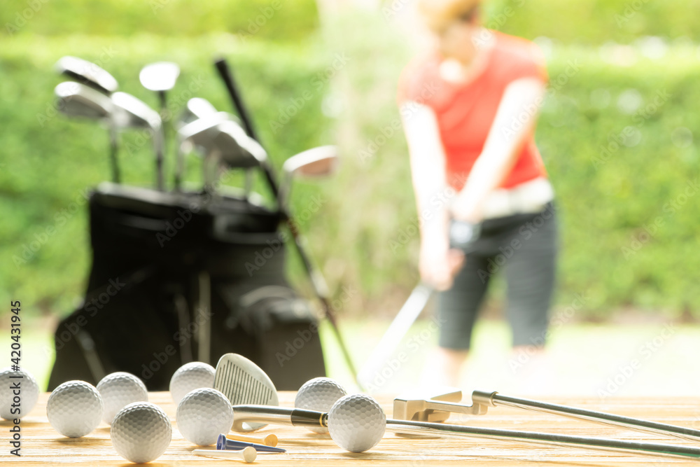 Wall mural golf balls, golf equipment and golf club on table on driving range with golfer in background