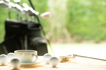Golf balls and golf club and coffee cup on table on driving range background