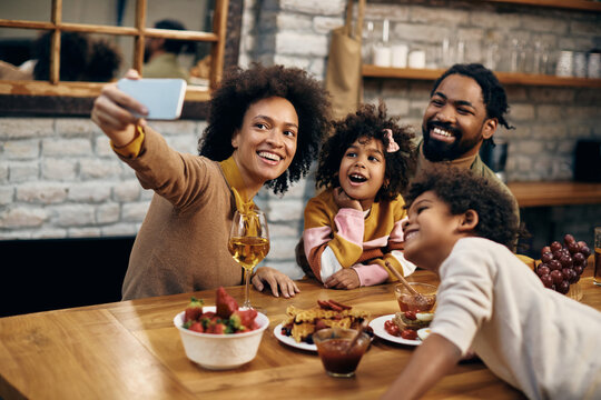Happy African American family taking selfie with cell phone at home.