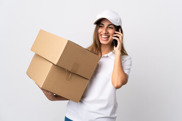 Young delivery woman over isolated white background keeping a conversation with the mobile phone with someone