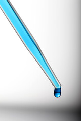 Pipette with blue liquid in with a droplet