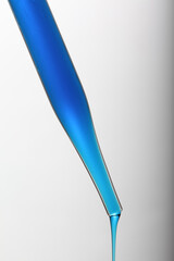 Pipette with blue liquid in with a droplet