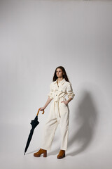 Fototapeta premium pretty woman in white suit holds hand in pocket umbrella in hands modern style