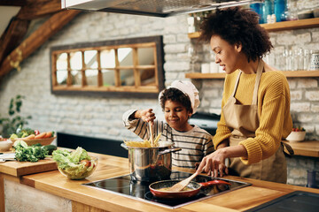 African American mother and son cooking together in the kitchen.