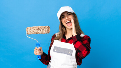Painter woman over isolated blue background shouting with mouth wide open
