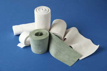 Medical bandage rolls and sticking plaster on blue background