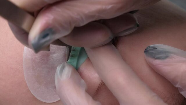 Extension and volumetric extension of long lush eyelashes for a lady in a beauty salon. Young woman with long lush eyelashes undergoes an eyelash care procedure, close-up