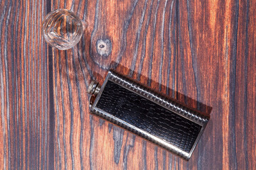 Hip flask and glass on a wooden table