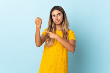 Young hispanic woman over isolated blue background making the gesture of being late