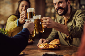 Close-up of friends toasting with beer in a bar.