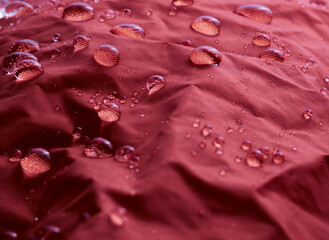 Water drops on waterproof membrane fabric. Detail view of texture of red waterproof cloth.