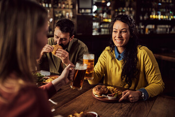 Happy woman toasting with female friend while having lunch in a pub.