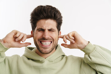 Displeased handsome man in sportswear plugging his ears
