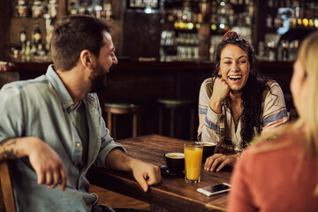 Young happy friends having fun while talking in a cafe.